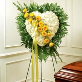 Heart-shaped white floral spray with yellow roses on a stand