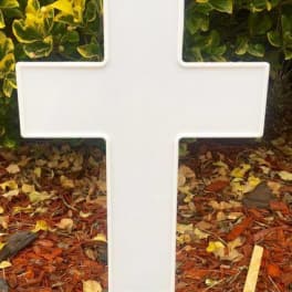 White cross-shaped memorial sign on a stake outdoors