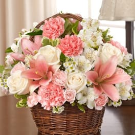 Pink and white flowers arranged in a wicker basket