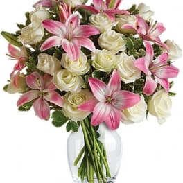 Pink lilies and white roses in a clear glass vase