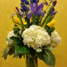 Bouquet of blue and purple flowers with white hydrangeas in a glass vase