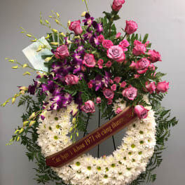 Standing floral wreath with pink roses, purple orchids, and white daisies