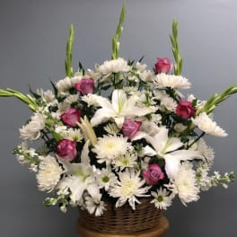 Basket arrangement of white lilies, daisies, and pink roses