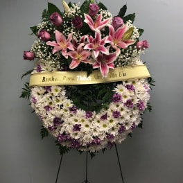 Standing floral wreath with pink lilies, roses, and white-purple daisies