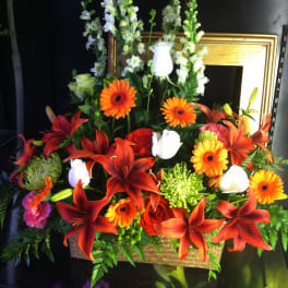 Tall basket arrangement of red lilies, orange gerberas, white callas and mixed flowers