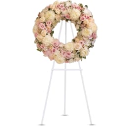 Round wreath of pale pink roses and cream chrysanthemums on a white standing easel