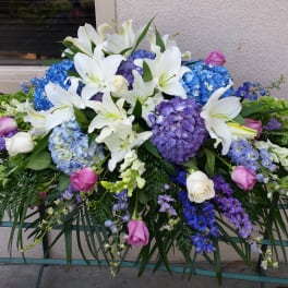 Large floral spray with white lilies, blue hydrangeas, and pink roses