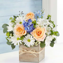 Peach roses and white daisies in a wooden box vase