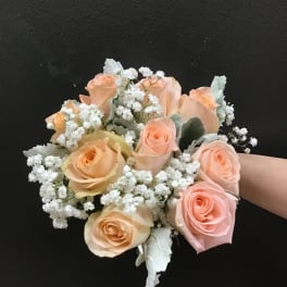 Handheld bouquet of peach roses and white baby's breath