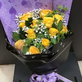 Bouquet of yellow roses with white baby's breath in black and purple wrapping
