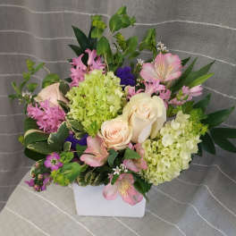 Mixed bouquet in a white square vase with pink and cream flowers