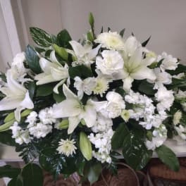 White lilies and chrysanthemums arranged in a low casket spray