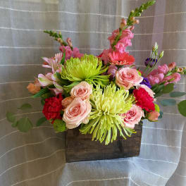 Mixed bouquet in a wooden box with pink roses and bright green chrysanthemums