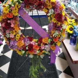 Large circular floral wreath on an easel with a purple ribbon