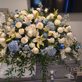 Large white and blue floral casket spray with roses and lilies