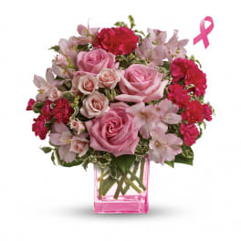 Pink roses and carnations in a pink glass vase with a ribbon