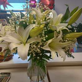 White lilies and baby's breath in a clear glass vase