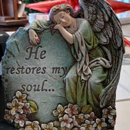 Decorative angel figurine leaning on a stone plaque with flowers