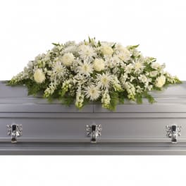 White floral casket spray with green accents on a silver casket