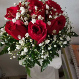 Red roses with white baby's breath in a white vase