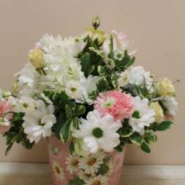 Pink and white flower arrangement in a decorative tin container