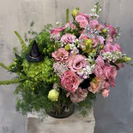Pink rose bouquet with green accents and a small black witch hat