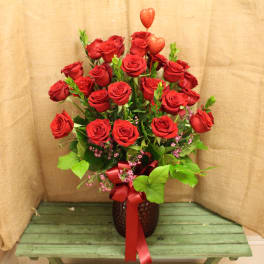 Red roses arranged in a vase with a red ribbon