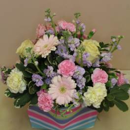 Pastel mixed flower arrangement in a striped box