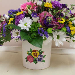 Mixed bouquet in a white ceramic pot with white, purple, pink, and yellow flowers