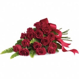 Cluster of long-stem red roses tied with a red ribbon bow and arranged in a flat fan shape.