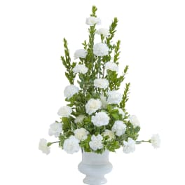 Tall arrangement of white carnations and greenery in a white urn-style vase