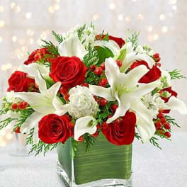 Red roses and white lilies arranged in a square glass vase