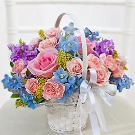 Basket of pink and blue flowers with a white ribbon bow