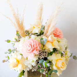 Pastel floral arrangement with roses and a pink dahlia in a gold vase