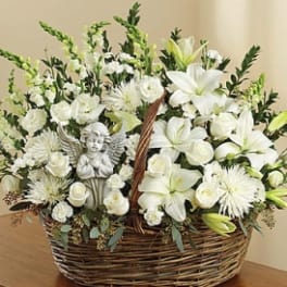 White floral basket arrangement with an angel figurine