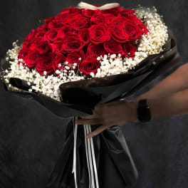 Bouquet of red roses with white baby's breath wrapped in black paper