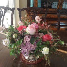 Pink and white rose arrangement in a silver vase on a table
