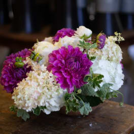 Low bouquet of purple, white, and cream flowers on a table