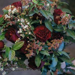 Hand-tied bouquet of deep red roses with white berry sprigs