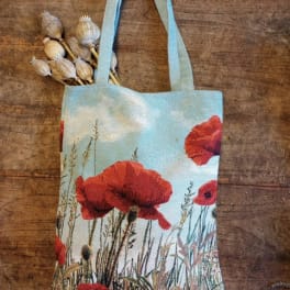 Tote bag with red poppy print and dried seed pods tucked in the handle