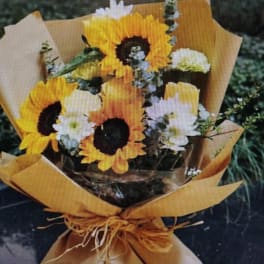 Bouquet of sunflowers and white daisies wrapped in brown paper