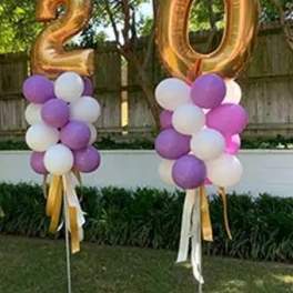 Two gold number balloons with purple and white balloon clusters