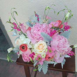 Pink floral arrangement with roses and peonies on a small table
