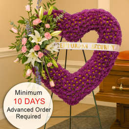 Tall purple heart-shaped funeral wreath with pink and white flowers on a stand