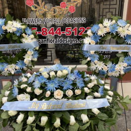 Three blue and white floral wreaths with memorial ribbons