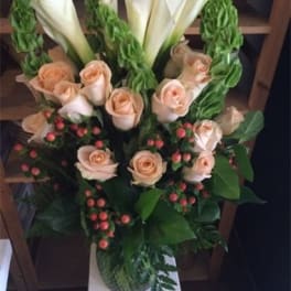 Bouquet of peach roses and white calla lilies with red berries