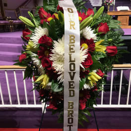 Large funeral wreath of red, white, and yellow flowers with a memorial ribbon