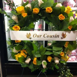 Yellow and white rose wreath on an easel with a memorial ribbon
