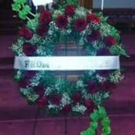 Heart-shaped floral wreath with red roses and a white ribbon