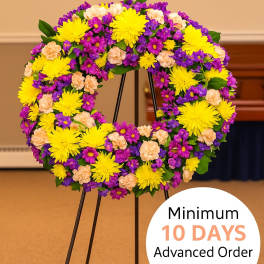 Standing wreath of yellow, purple, and peach flowers on a metal easel